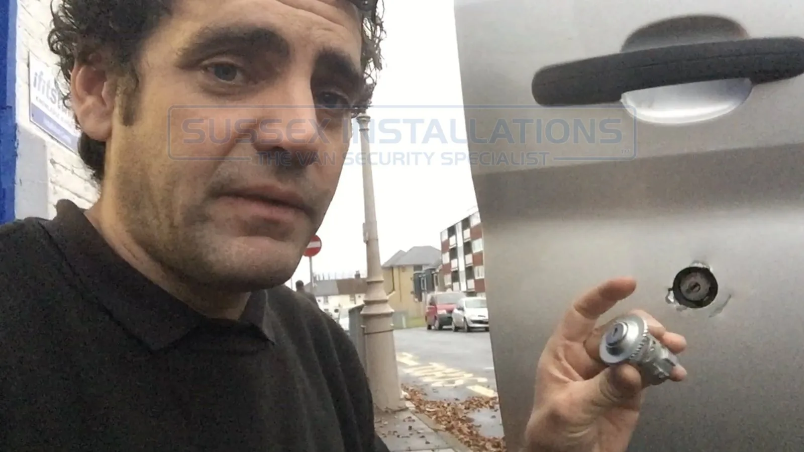 Jeff Scott holding a drilled-out lock barrel next to a Ford Transit driver's door with a hole drilled through the panel