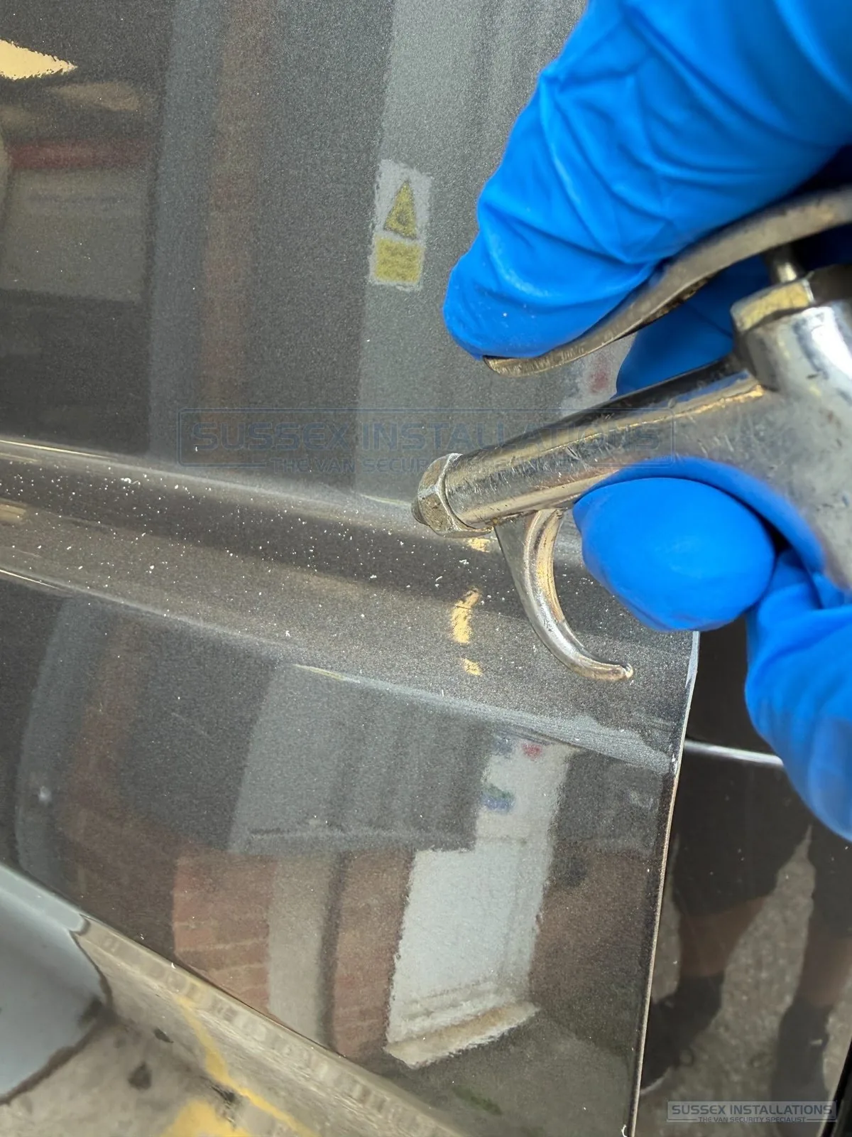 Compressed-air blow gun removing metal swarf from van paintwork