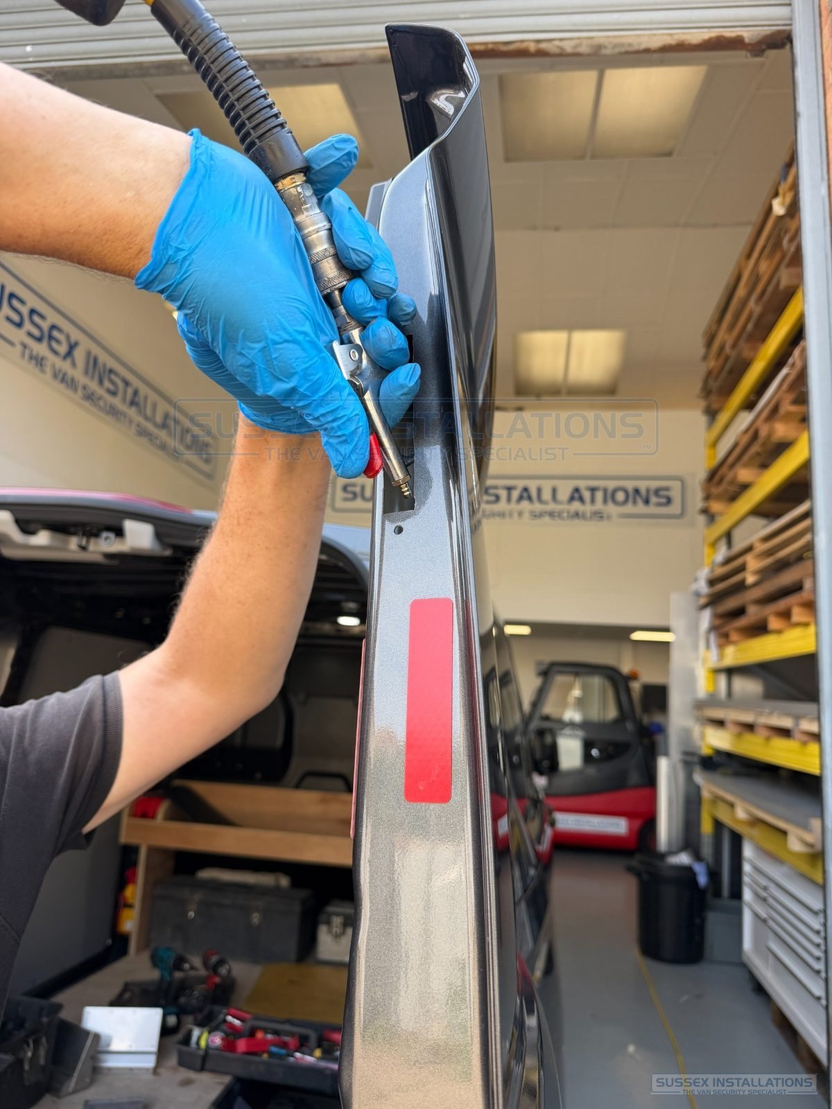 Compressed-air blow gun cleaning a rear van door edge