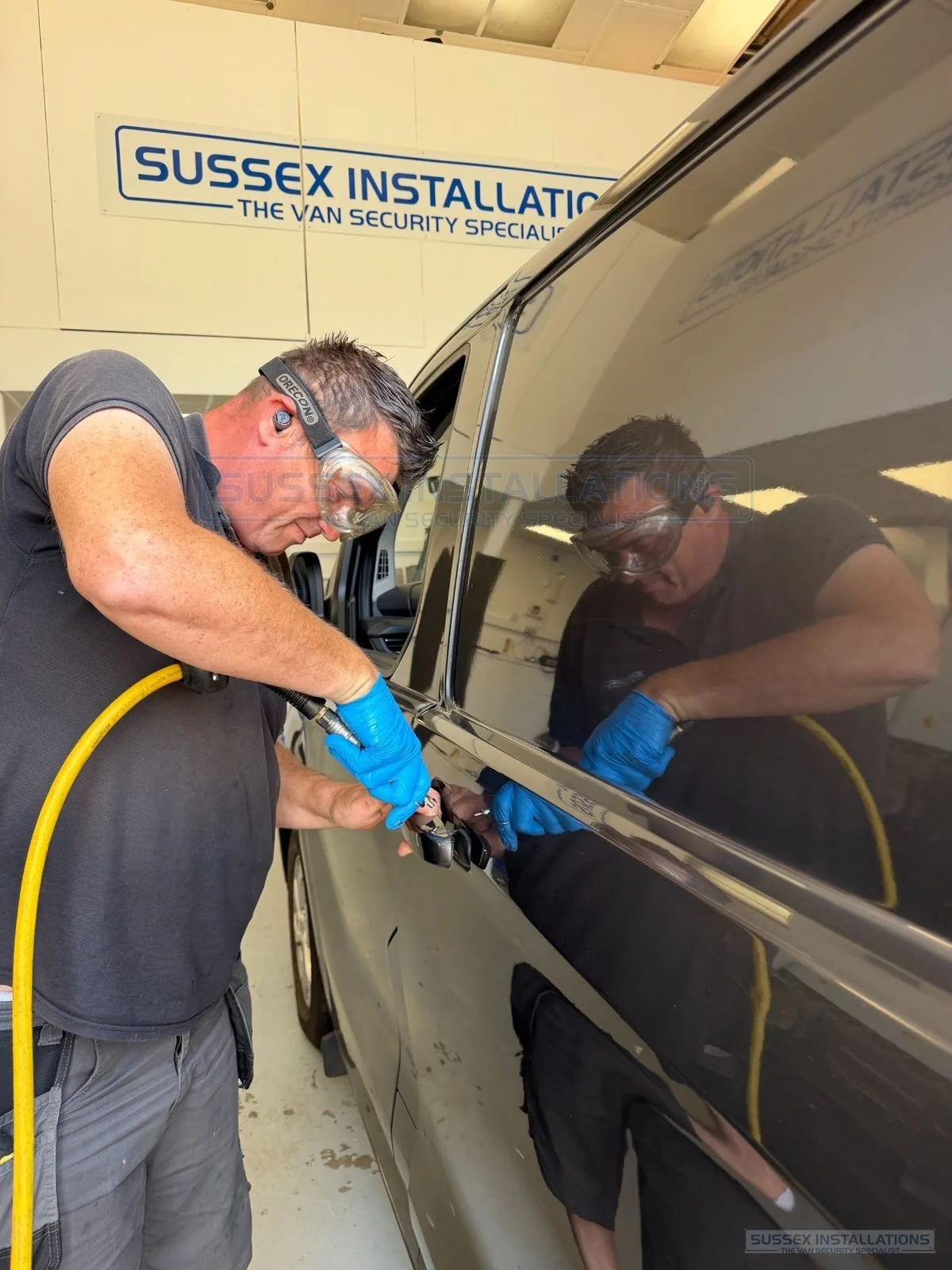Professional van-security installer using an air blow gun