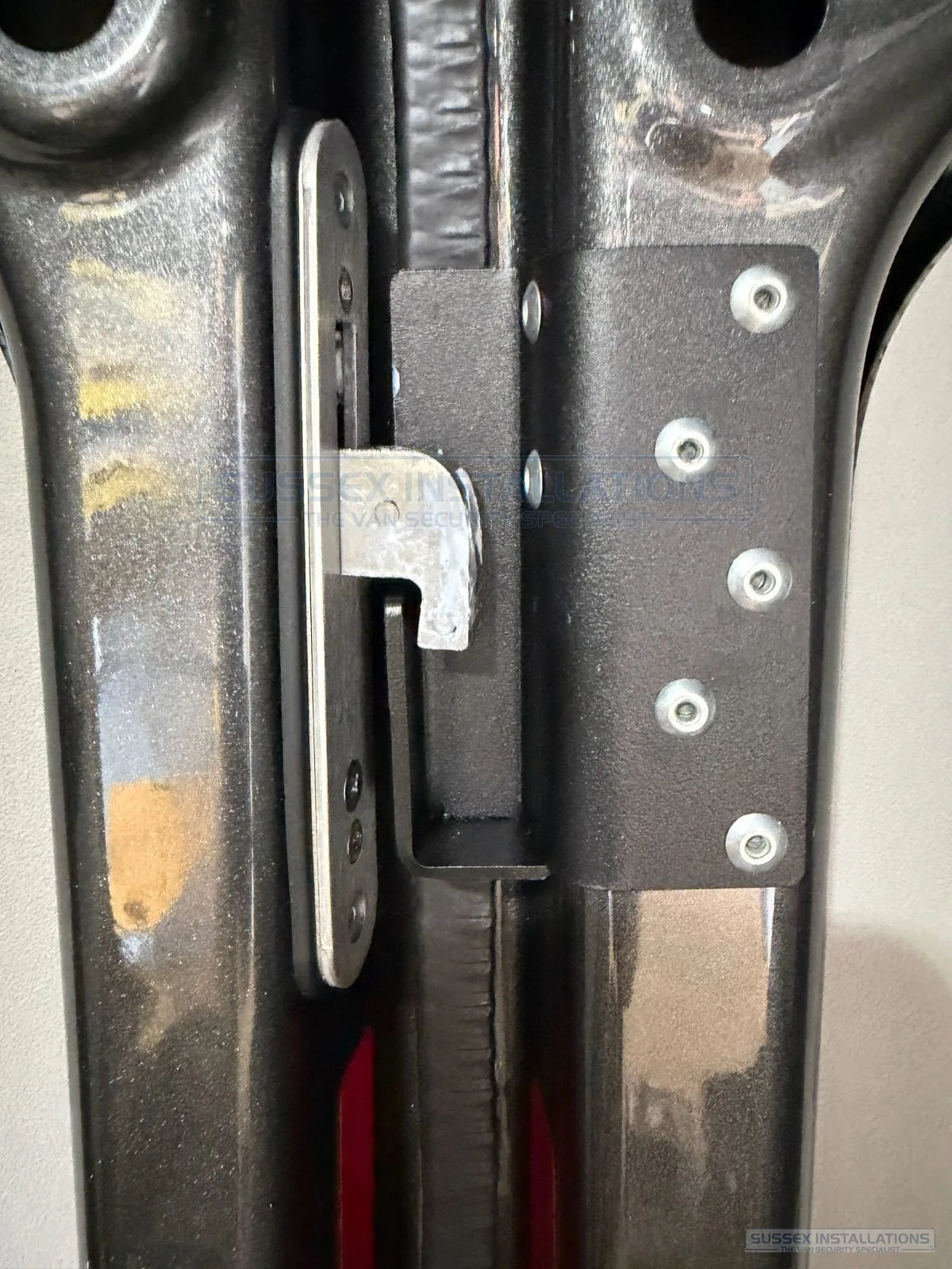 Close-up of a hook lock's hook-shaped bolt thrown behind the keep bracket fitted to the opposing door or body of the van