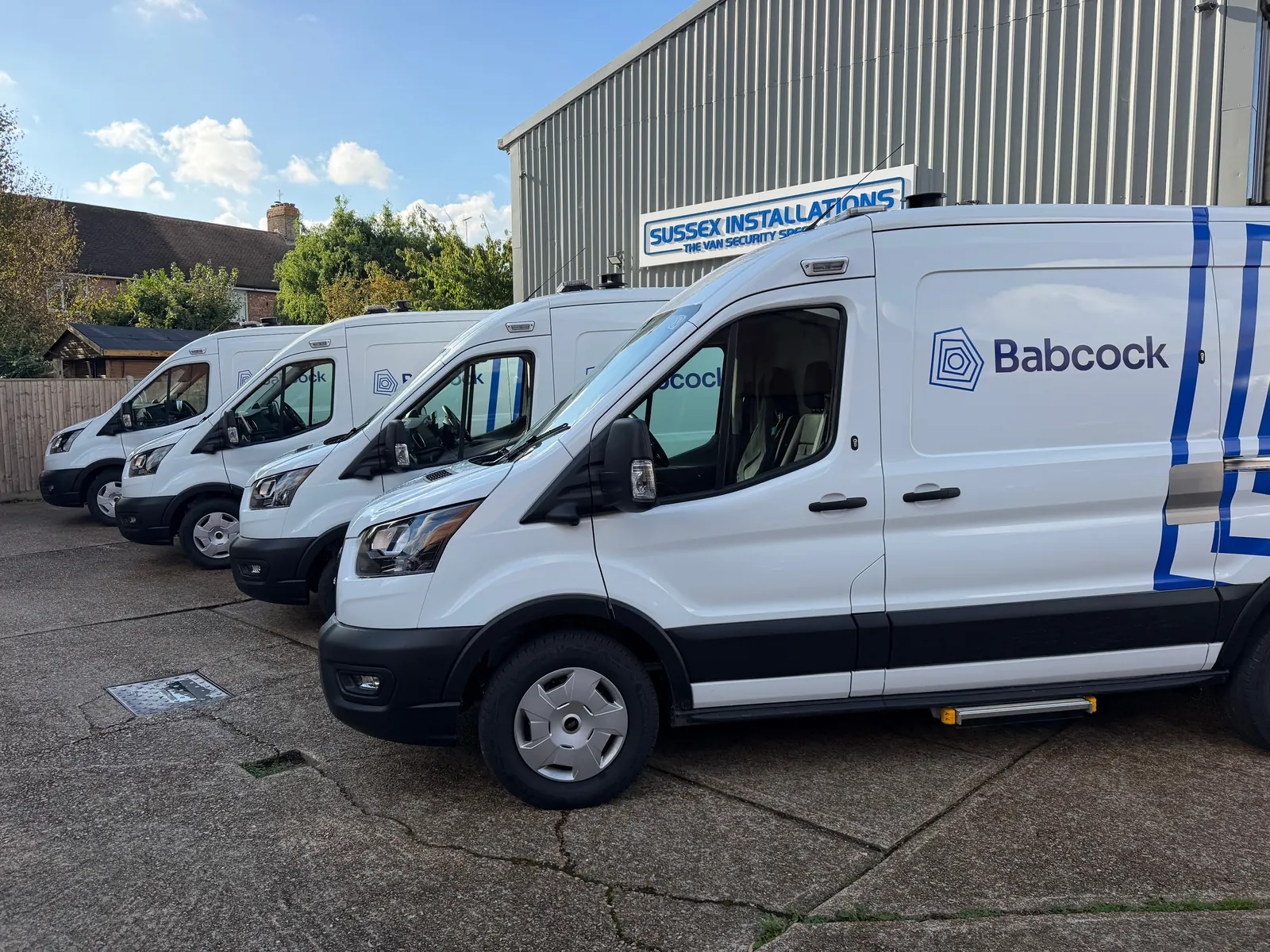 Row of service vans parked at the Sussex Installations workshop, viewed from the front